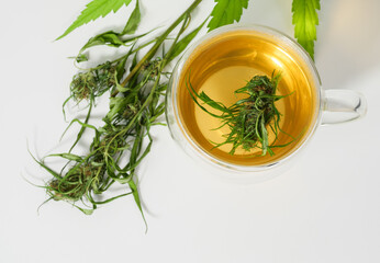 Cannabis herbal tea cup with  marijuana fresh green leaves and   bud in  glass cup on white background, CBD medical drink