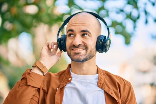 Young hispanic bald man smiling happy using headphones at the city