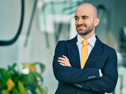 Young hispanic bald businessman with arms crossed smiling happy at the city.