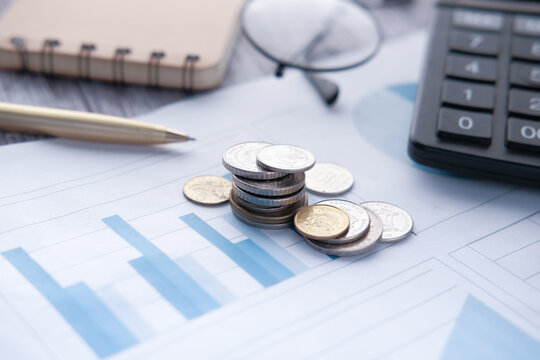 Stack Of Coins, Financial Graph, Calculator And Notepad On Table 