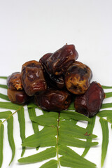 Dry dates with green leaves isolated on white background. Top view. Flat lay pattern