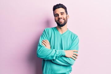 Young handsome man with beard wearing casual sweater happy face smiling with crossed arms looking at the camera. positive person.