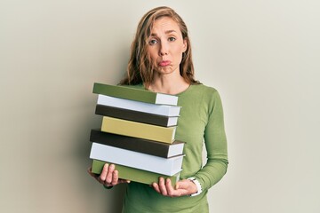 Young blonde woman holding a pile of books depressed and worry for distress, crying angry and afraid. sad expression.