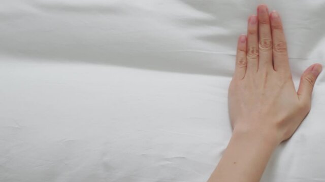 Hand touching very soft on a wrinkled white cloth and swept it down completely.