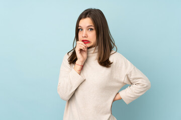 Teenager girl isolated on blue background nervous and scared