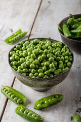 Fresh green peas. Fresh green peas pods and green peas in the bowl on wooden background.
