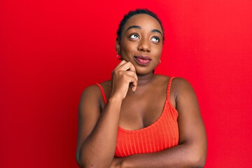 Young african american woman wearing casual style with sleeveless shirt thinking concentrated about doubt with finger on chin and looking up wondering