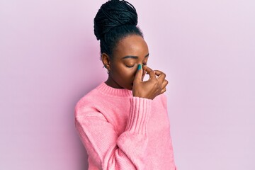 Young african american woman wearing casual winter sweater tired rubbing nose and eyes feeling fatigue and headache. stress and frustration concept. - obrazy, fototapety, plakaty