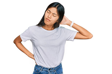 Obraz premium Beautiful young asian woman wearing casual white t shirt suffering of neck ache injury, touching neck with hand, muscular pain