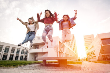 Portrait of a group of Asian female friends enjoying time together while jumping in the air outdoors.