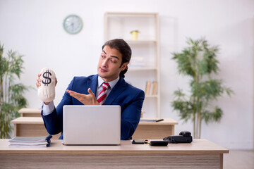 Young male employee holding moneybag in the office