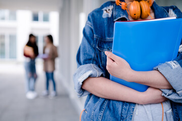 Close-up of a college student holding folders while standing at the hallway. Education concept.
