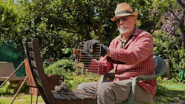 uomo anziano pulisce griglia barbecue