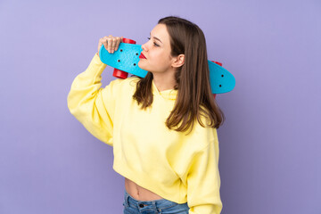 Teenager girl isolated on purple background with a skate with happy expression