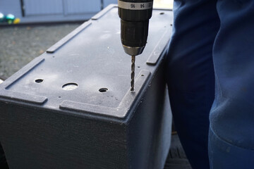 a man is drilling holes in the bottom of a flower pot