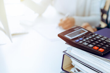 Calculator and binders with papers are waiting to be processed by business woman or bookkeeper...