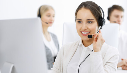 Call center. Group of diverse operators at work. Beautiful woman in headset communicating with customers of telemarketing service. Business concept