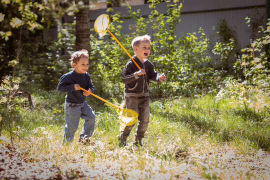Two boys with butterfly nets running in countryside. Image with selective focus