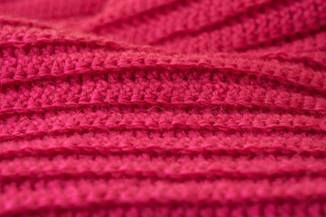 The structure of a knitted canvas of pink wool threads.