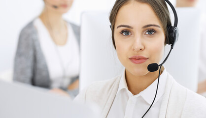 Call center. Group of diverse operators at work. Beautiful woman in headset communicating with customers of telemarketing service. Business concept