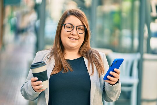 Young plus size businesswoman using smartphone and drinking coffee at the city. - Powered by Adobe