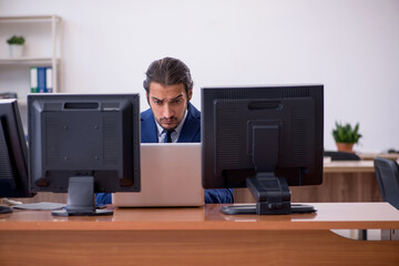 Young male employee in multitasking concept