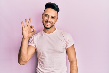 Young arab man wearing casual clothes smiling positive doing ok sign with hand and fingers. successful expression.