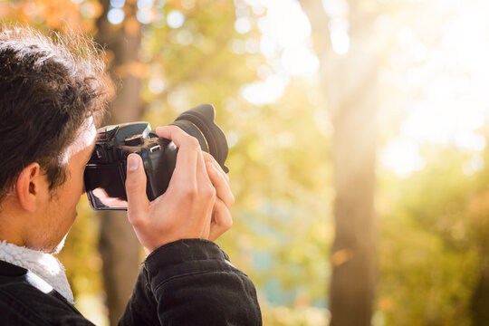 Taking photos in autumn season. Student taking pictures of a fall forest with a bright sunlight.