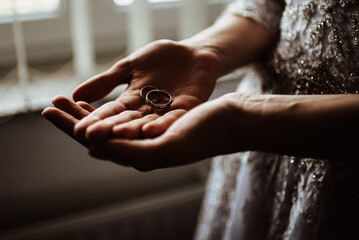 the bride holds wedding rings in her hands