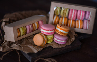 Boxes with multi-colored pasta cakes lie on the background of the cakes themselves on a dark background
