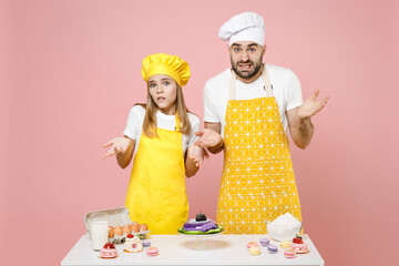 Teen mistaken confused girl dad chef cook confectioner baker wear yellow apron toque cap at table...