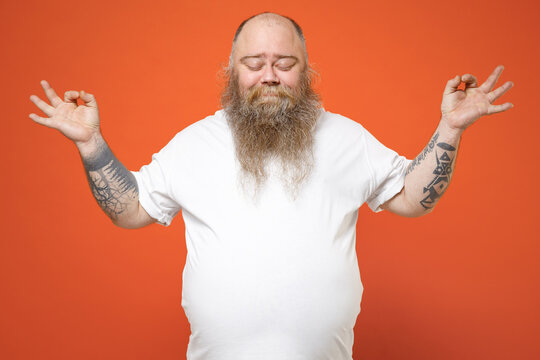 Fat Spiritual Tattooed Pudge Obese Chubby Overweight Bearded Man Has Big Belly In White Tshirt Hold Spread Hands In Yoga Gesture Relax Meditate Calm Down Isolated On Orange Background Studio Portrait