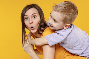Happy young woman have fun with cute child baby boy 5-6-7 years old in violet t-shirt stand behind...