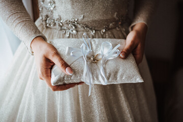 the bride holds in her hands a pillow with wedding rings