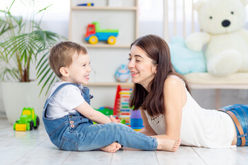the mother talks to the baby boy or plays at home with educational toys in the children's room. A happy, loving family.