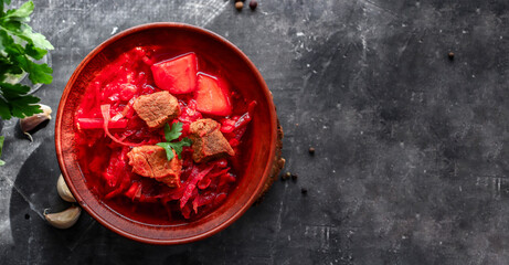 Red borsch with vegetables and meat in a clay plate. Steam from hot tomato soup. Dark background. Delicious healthy lunch. Top view. Copyspace