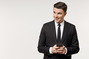Young successful employee business corporate lawyer man wear classic formal black grey suit shirt tie work in office hold mobile cell phone look aside isolated on white background studio portrait.