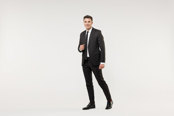 Obraz na płótnie Canvas Full length young happy smiling successful employee business corporate lawyer man wear classic formal black grey suit shirt tie work in office walk going isolated on white background studio portrait.