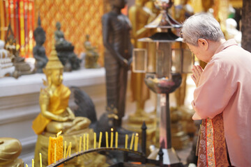 old asian senior woman traveler tourist praying at buddhist temple.