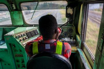 African man train driver sitting interior to control place of train with talking radio communication