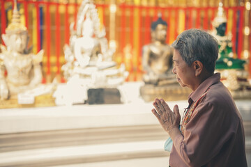 old asian senior woman traveler tourist praying at buddhist temple.