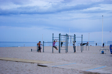 Fototapeta na wymiar Young boys making calisthenics in the afternoon at a spanish beach.