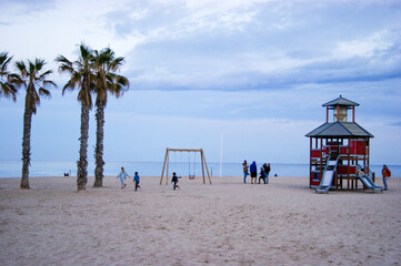 Children playing in swings at a spanish mediterranean beach.