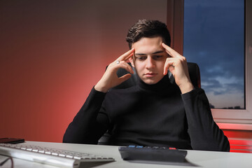 Young businessman is puzzled by something. He looks at the calculator with displeasure. Guy is...