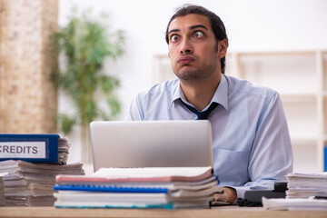 Young male employee and too much work in the office