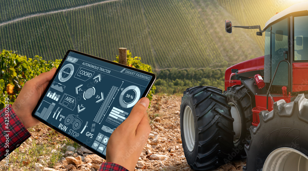 Poster a farmer remotely controls an autonomous tractor in a vineyard. harvest.