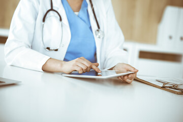 Unknown woman-doctor standing in clinic and using tablet pc, close-up. Data and best service in medicine and healthcare