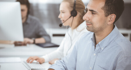 Business people working together in modern office. Happy smiling adult businessman using pc computer with colleagues. Teamwork and partnership concept