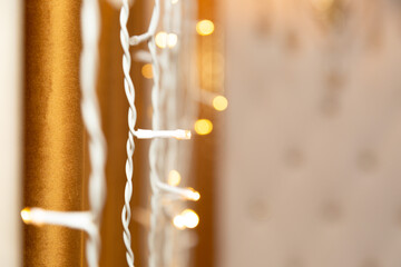 Garland lights are burning near the wall on a brown background, bokeh.