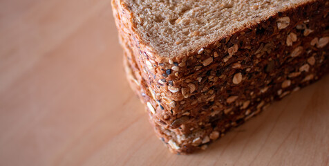 closeup corner slices of fresh baked whole wheat multi grain bread on cutting board
